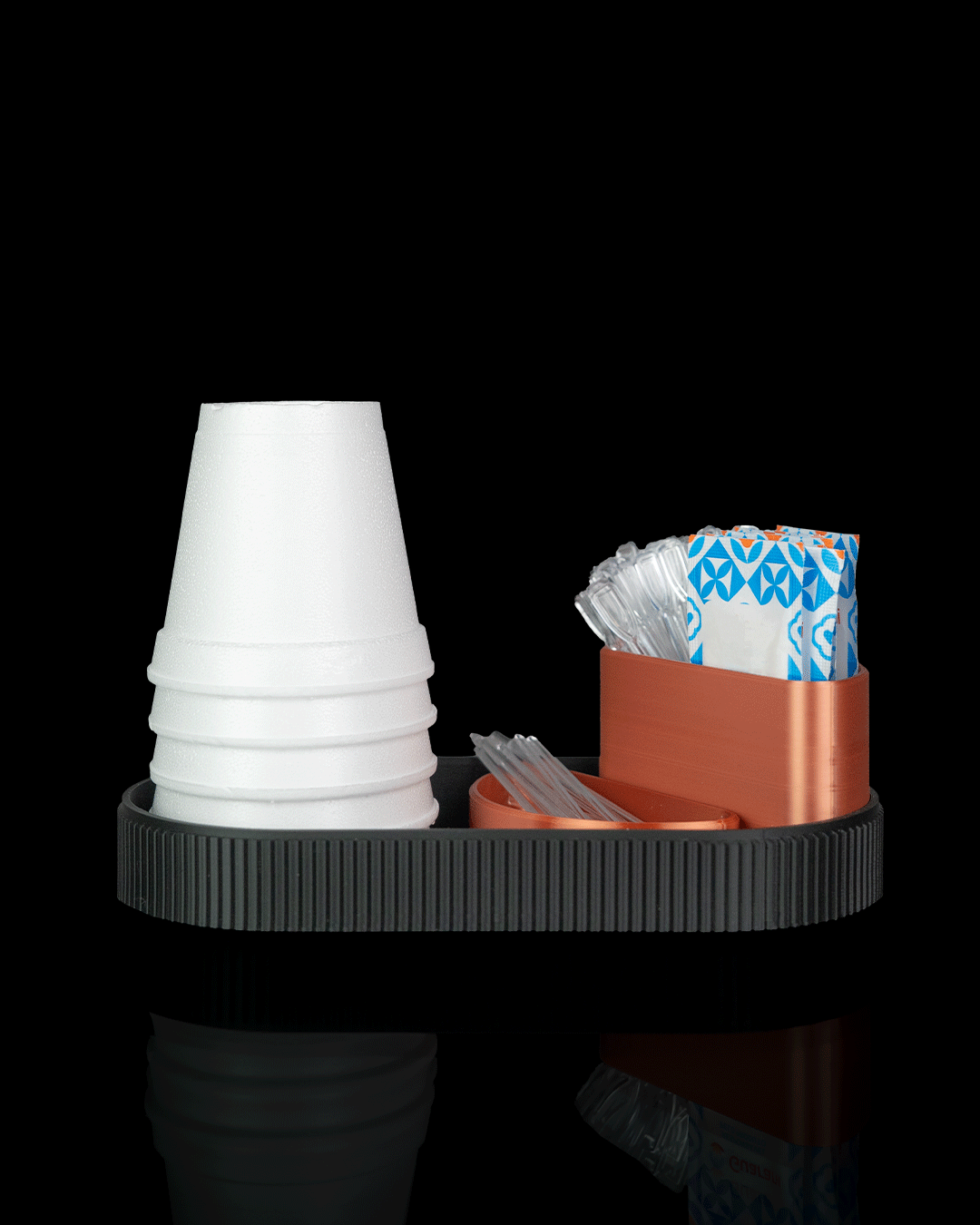 Organizador cantinho do café impresso em 3D, com bandeja oval preta texturizada, copos descartáveis brancos e compartimentos para sachês na cor cobre.
