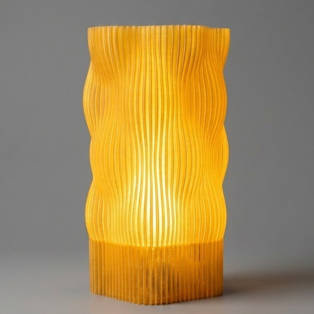 Luminária de mesa Bubble amarela impressa em 3D com design ondulado e linhas verticais, acesa emitindo luz quente e suave sobre fundo cinza neutro.